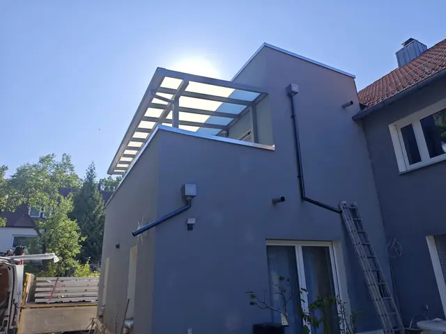 Moderne Überdachung aus Aluminium an einem Haus mit blauer Fassade