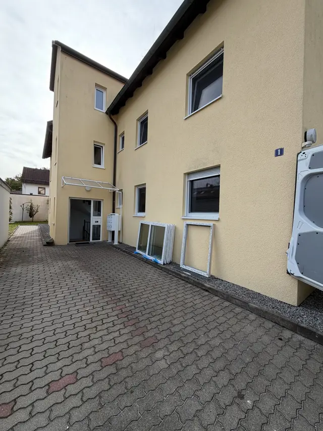 Mehrfamilienhaus mit neuen Fenstern, davor der Hof